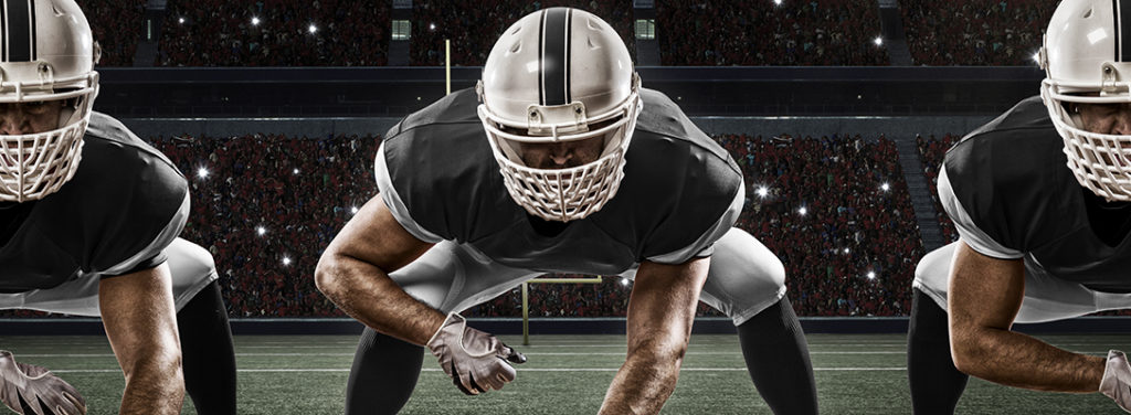 Football Players with a Black uniform on the scrimmage line, on a stadium.